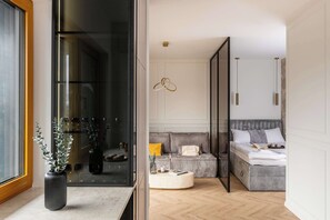 A modern bedroom with a bed, bedside table, and a window with a view. - Cozy Studio in Krakow | Balcony, Parking, Air Conditioning (Kraków)