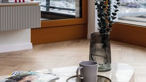 Moderni huone, jossa on suuri ikkuna, patteri, lehti, muki ja kasvi.
