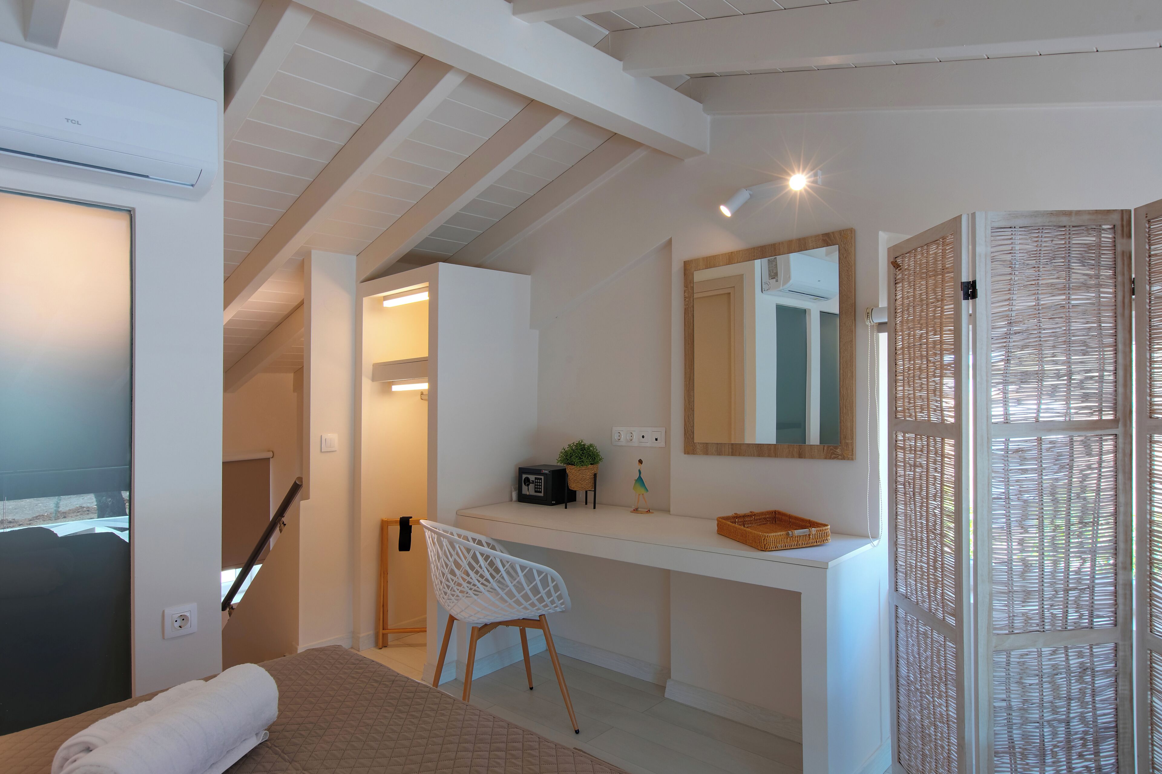 Een moderne hotelkamer met een bed, een bureau, een stoel, een kleine plant en een spiegel.