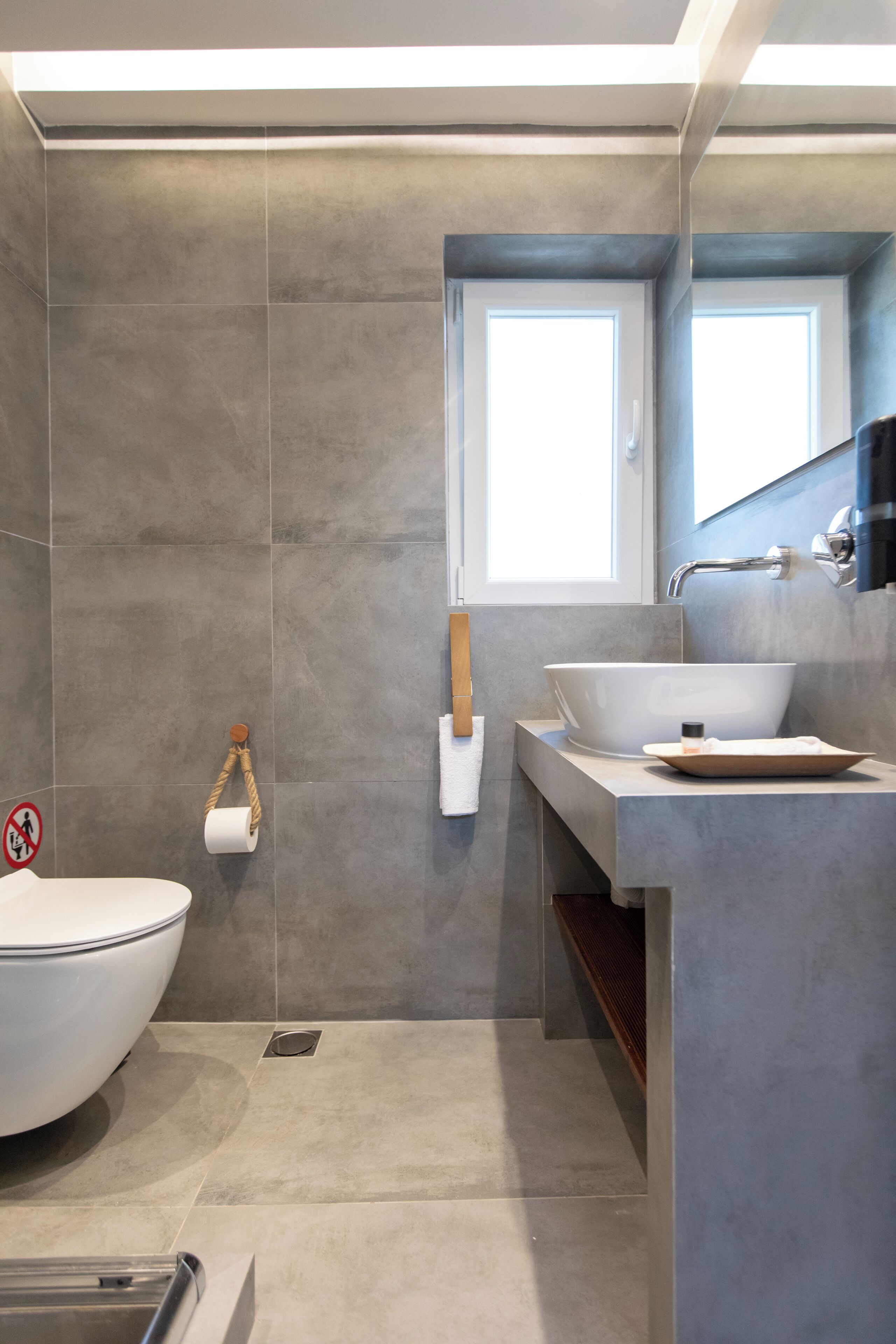 A modern bathroom with a large bathtub, a sink with a vessel basin, and a window above the mirror.