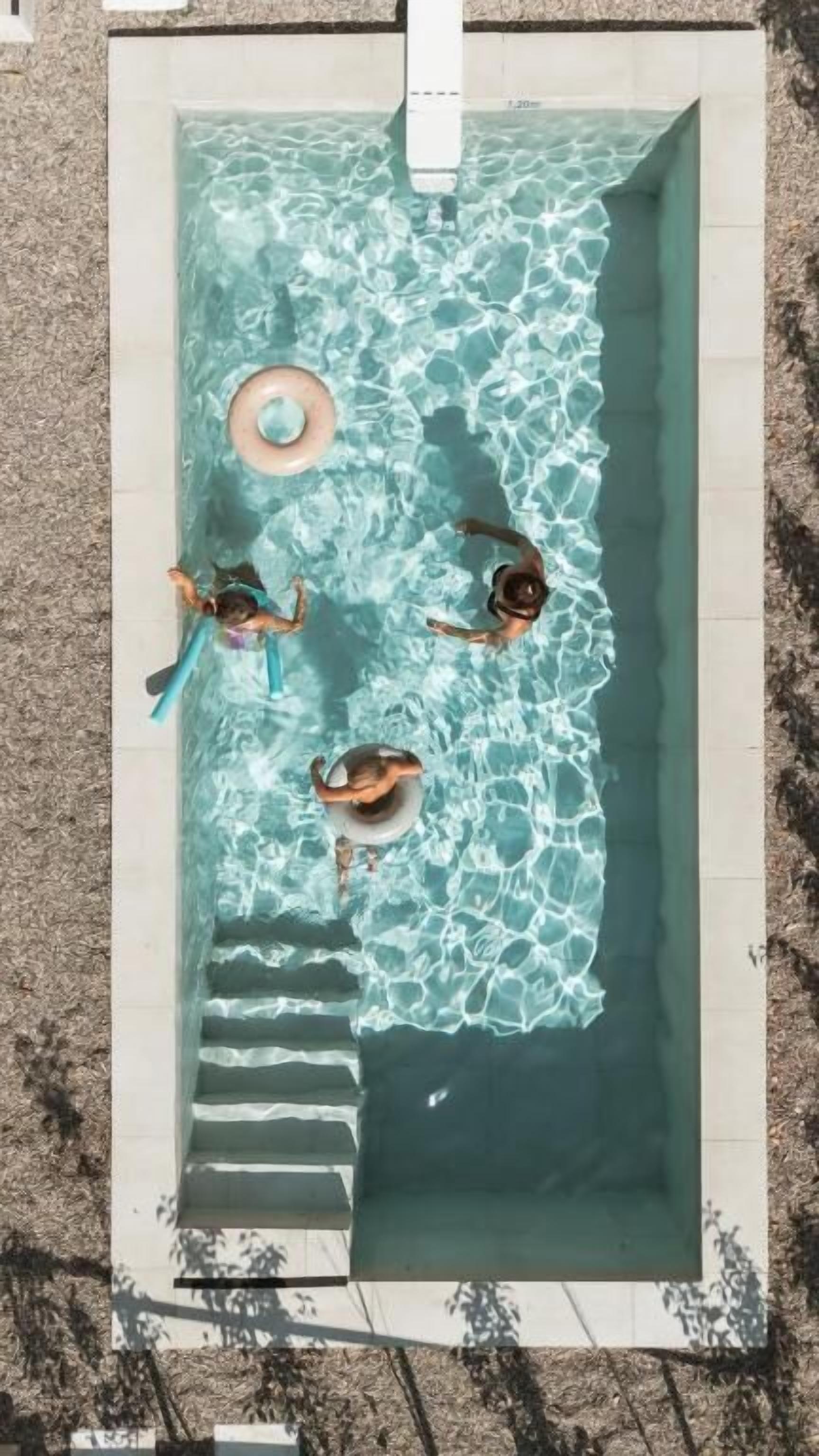 Et rektangulært swimmingpool med klart vand, trin ned til det og en flydende badering.
