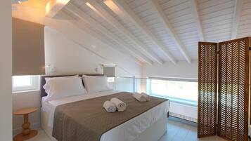 Un dormitorio con cama, mesitas de noche, una ventana y vistas al exterior.