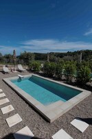 Piscina rectangular con agua azul cristalina, rodeada por un área de grava con piedras para pisar.