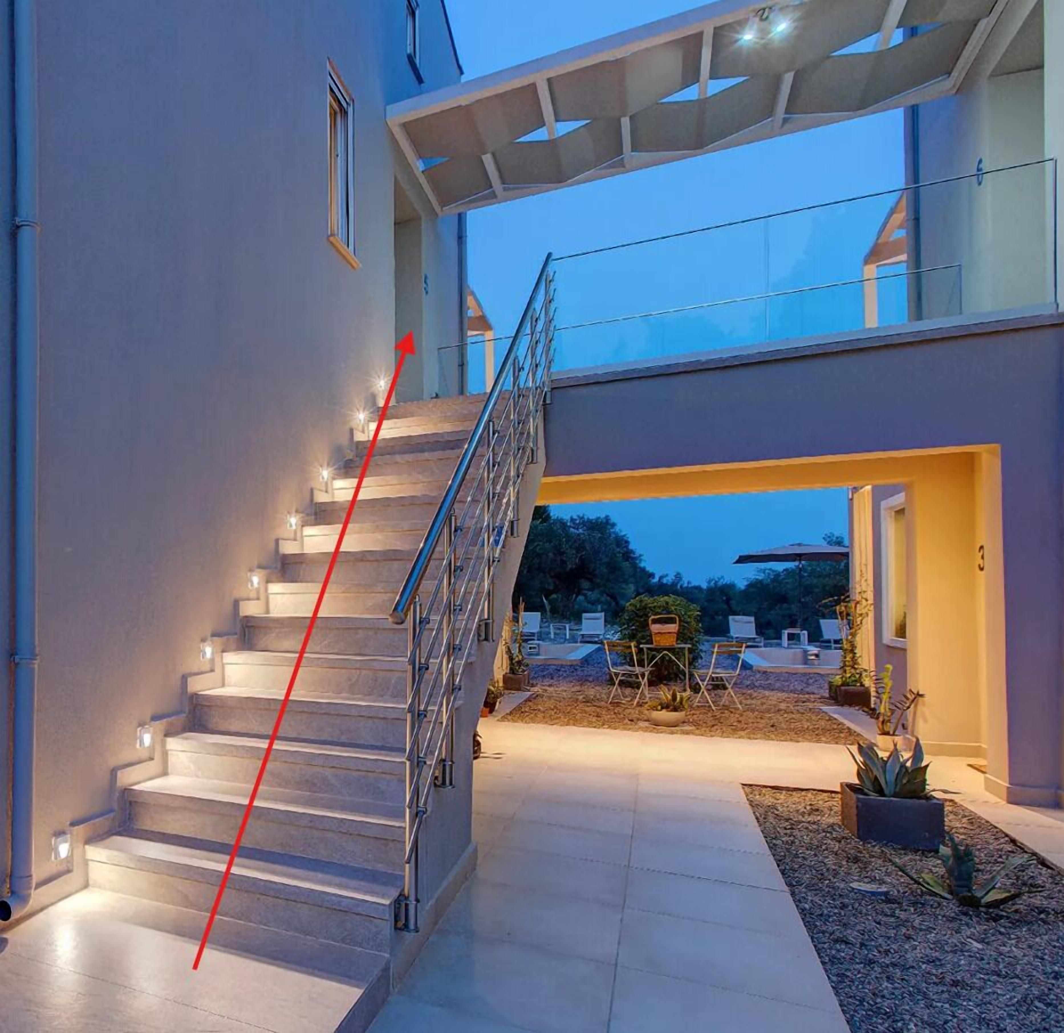 Une maison moderne avec un escalier menant à un espace extérieur abrité.