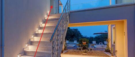 Une maison moderne avec un escalier menant à un espace extérieur abrité.