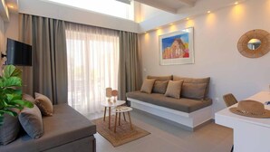 A modern living room with a sofa, a coffee table, and a TV. - KAELA Pool Villas (Agios Nikolaos)
