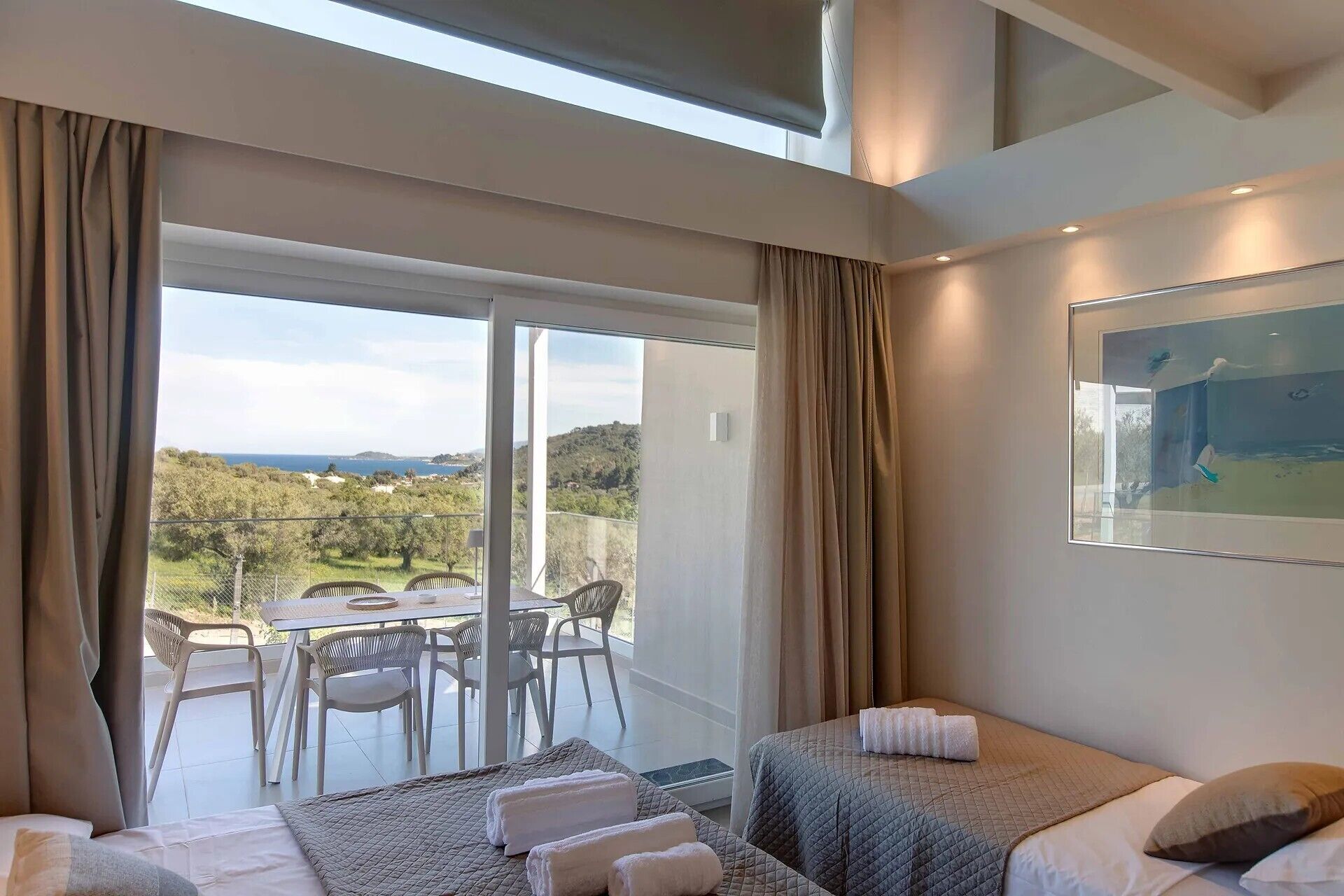 A hotel room with a balcony, a bed, a table, and chairs.