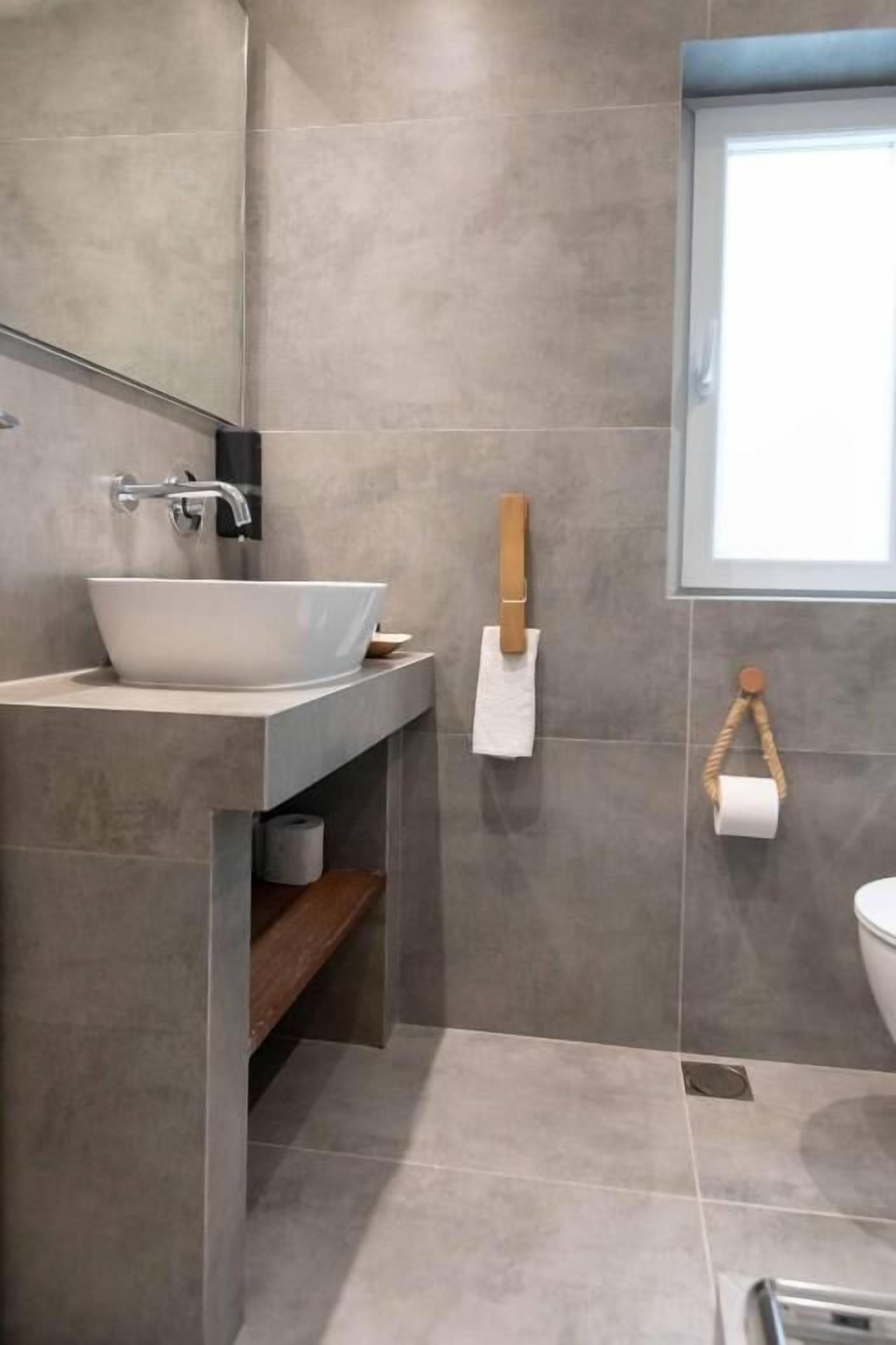 A modern bathroom with a vessel sink, a mirror, a towel rack, and a toilet.