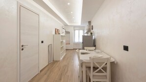 Una cocina moderna con armarios blancos, una mesa de comedor con sillas y vistas al área de comedor.
