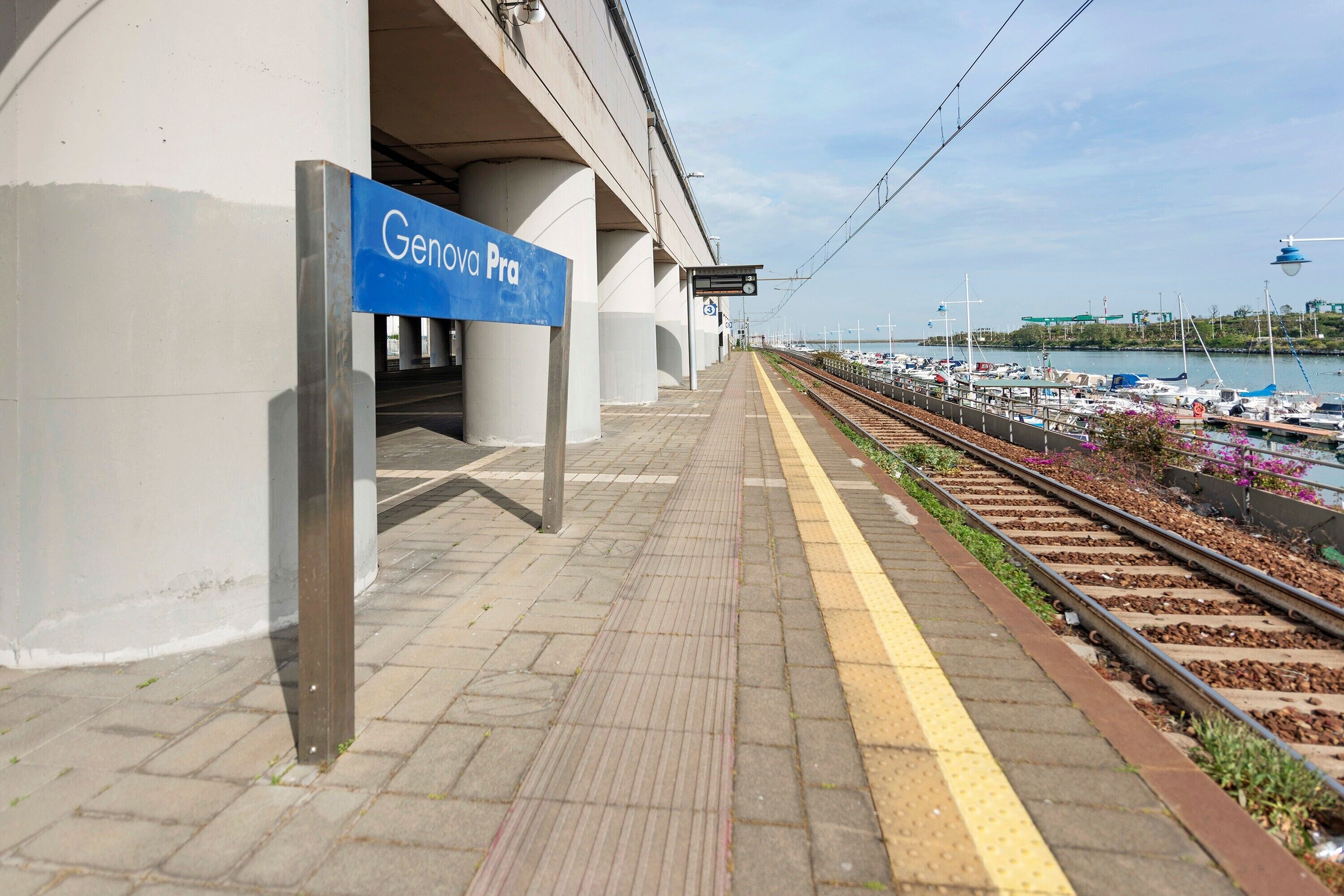 A train station platform with a sign reading 'Genova Pra.'