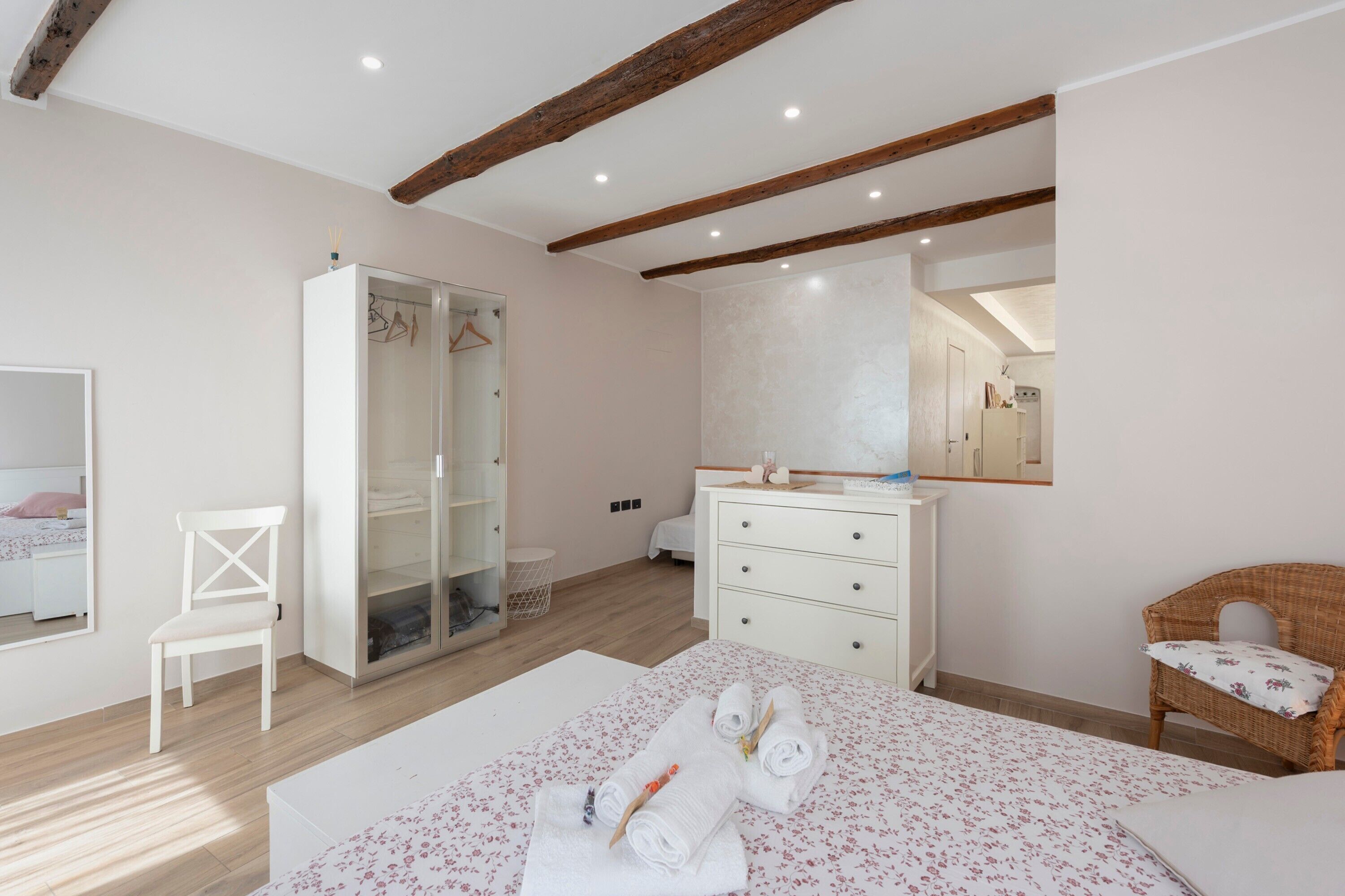 Une chambre à coucher comprenant un lit, une armoire, une commode, une chaise et un miroir.