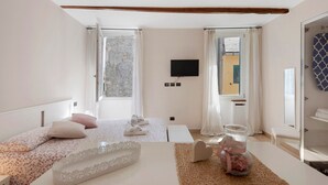 Una habitación de hotel con cama, televisión, ventana y baño.