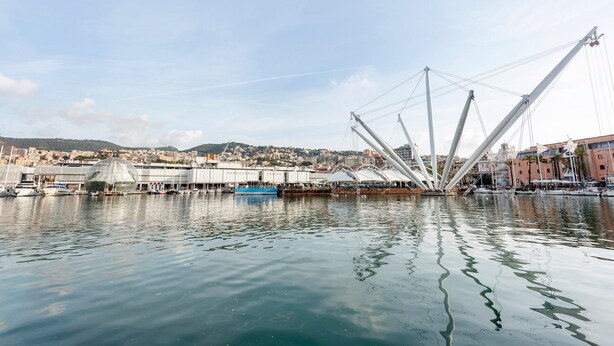 Vista al agua con un puente moderno, barcos y un paisaje urbano de fondo.
