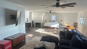 A spacious bedroom with a large bed, a ceiling fan, a TV mounted on the wall, and a dining area with a table and chairs. - Waterfront Studio minutes from Downtown Annapolis and Naval Academy (Edgewater)