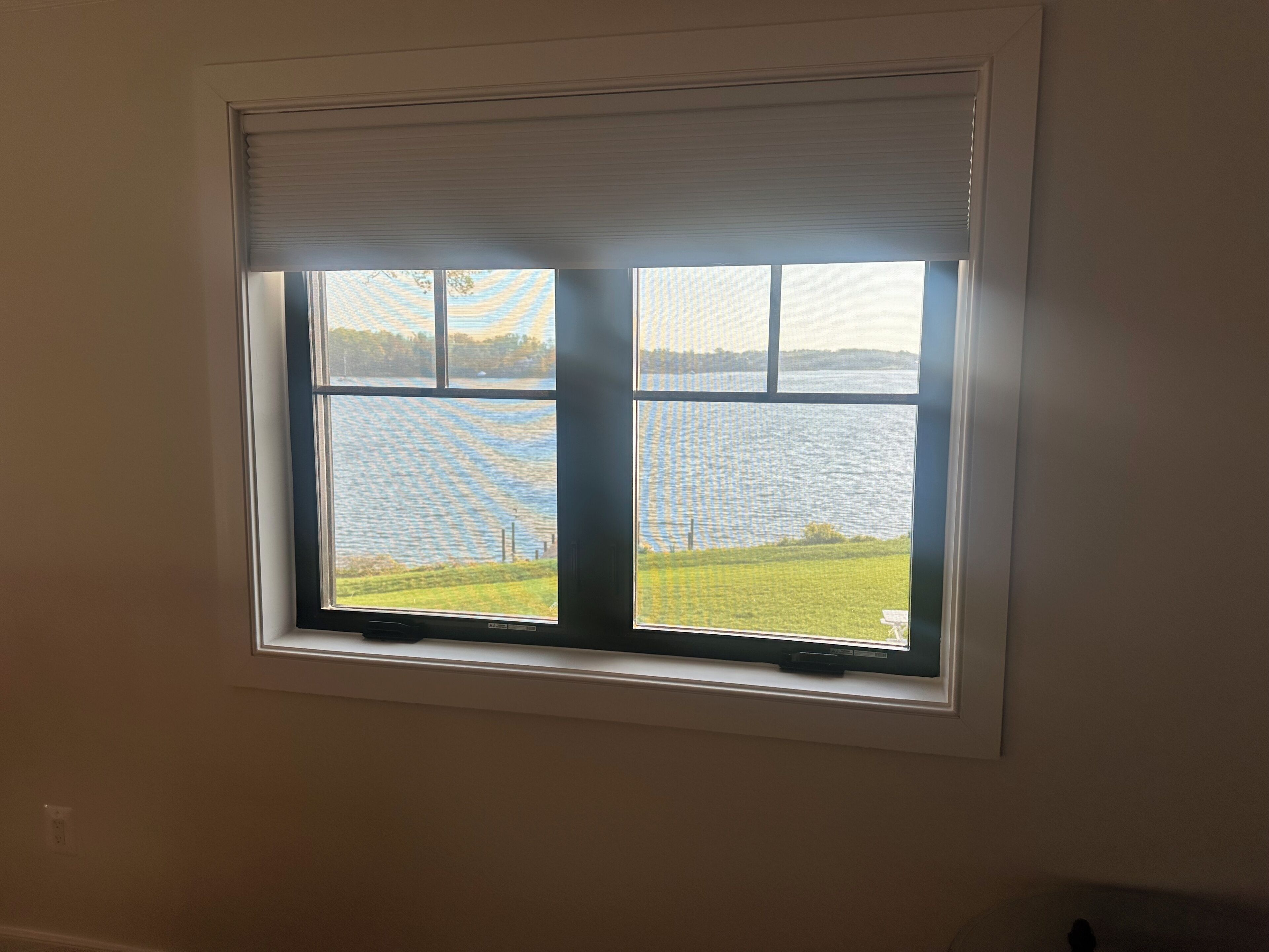 A window with a view of a body of water and a grassy area.
