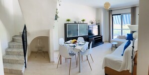A modern living space with a dining area, a sofa, and a staircase. - Edificio Azul V Dúplex 2º (Playa de Gandía)