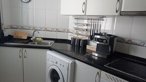 Une cuisine équipée d’un lave-linge, d’une machine à café et d’une horloge murale.