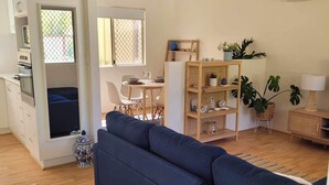A modern living room with a sofa, dining table, and kitchen area. - Enjoy a relaxing stay at this cosy one bedroom granny flat near the sea (Warnbro)