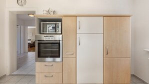 Eine Küche mit Mikrowelle, Backofen und Kühlschrank, mit Holzausstattung und einer Uhr an der Wand.