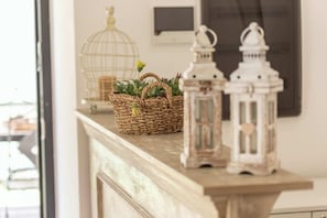 A fireplace mantel with a woven basket, two white lanterns, and a birdcage. - Versailles Suite (Napoli)