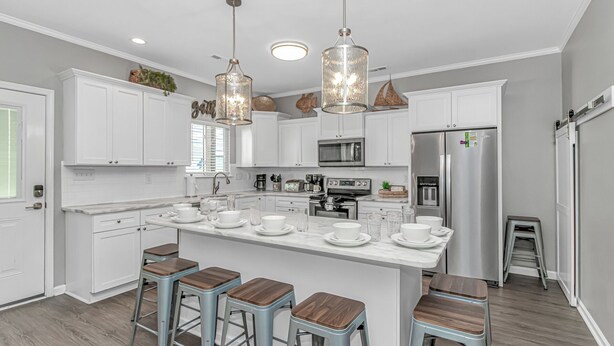 A modern kitchen with white cabinetry, stainless steel appliances, and a central island with stools. - 7 Bedrooms-OceanLakes-Sleeps18-GolfCart Included (Myrtle Beach)