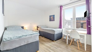 Un dormitorio con dos camas, un escritorio y una ventana.