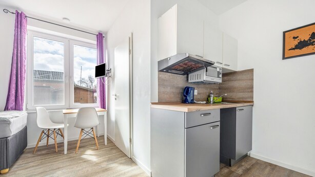 Una cocina moderna con armarios grises, una encimera de madera y una campana extractora empotrada.