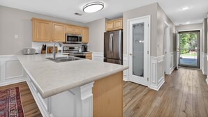 Una cocina moderna con armarios de madera, electrodomésticos de acero inoxidable y una isla de mármol.