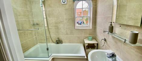 A bathroom with a bathtub, a sink, a window, and a shower.