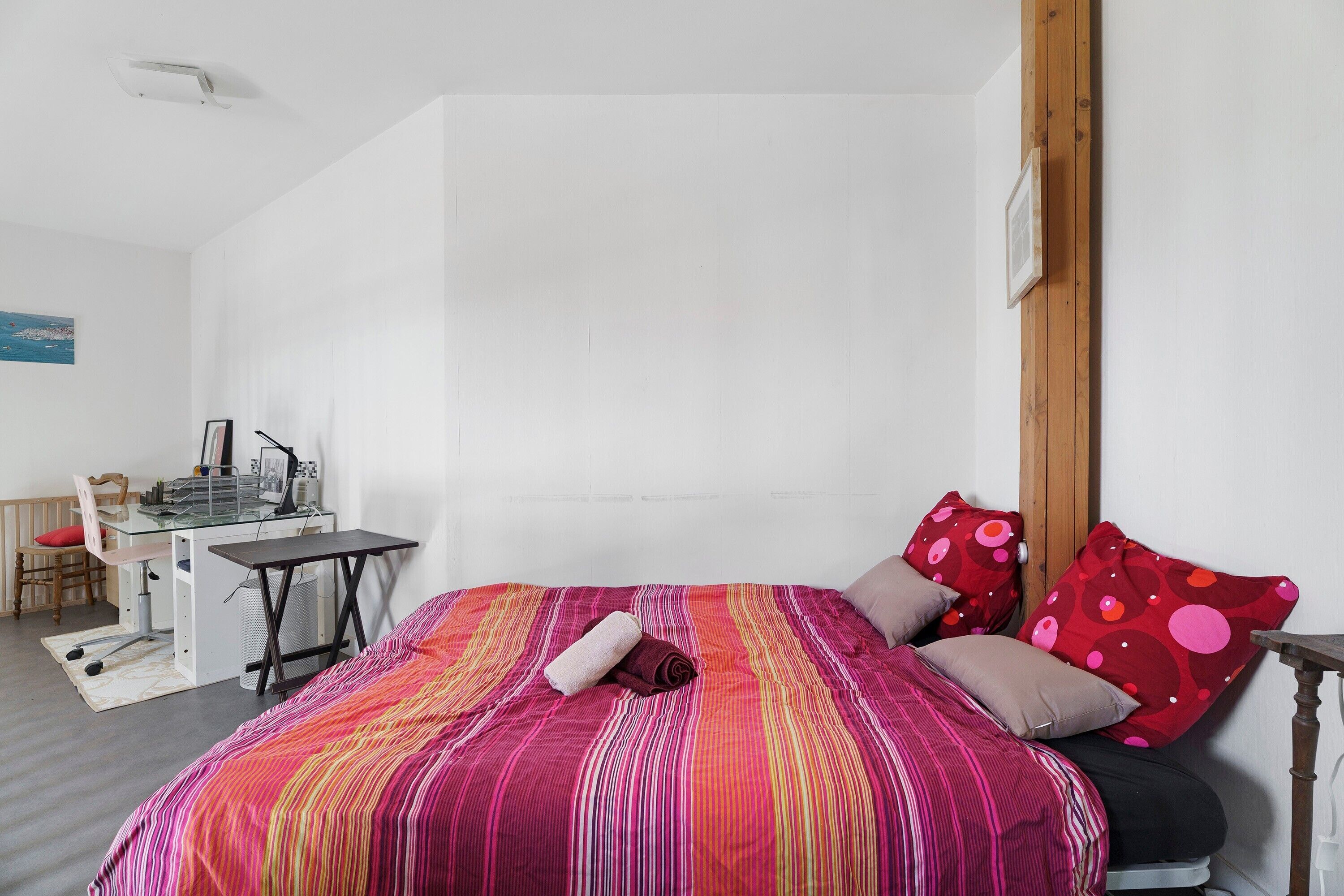 Un dormitorio con una cama, un escritorio y una silla.