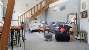 Un salon avec un escalier, un canapé, une table basse et une petite table ronde.