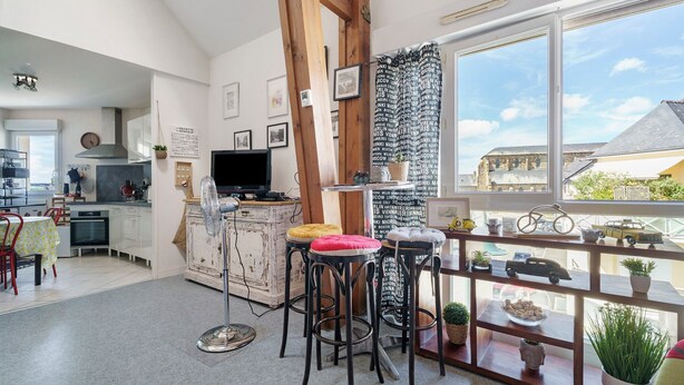 Une cuisine moderne avec un coin repas, des poutres en bois et une vue sur la ville.