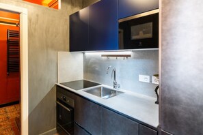 A compact kitchen with a double sink, stainless steel appliances, and dark cabinetry. - Historic and elegant Catullo residence (Verona)