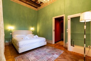 A bedroom with a bed, a patterned rug, a chandelier, and a lamp. - Historic and elegant Catullo residence (Verona)