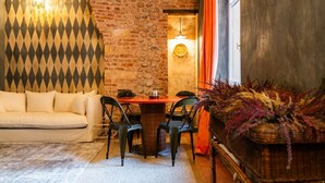 A cozy room with a brick wall, a patterned wall, a sofa, a table with chairs, and a decorative plant. - Historic and elegant Catullo residence (Verona)