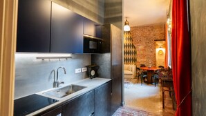 A compact kitchen with a sink, microwave, and cabinets, leading to a dining area with a table and chairs. - Historic and elegant Catullo residence (Verona)