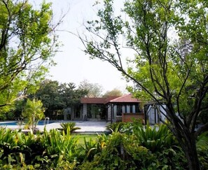 A house with a swimming pool, surrounded by lush greenery and trees. - The Mannat Farms (Taoru)