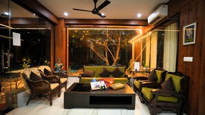 A modern living room with a sofa set, a coffee table, and a ceiling fan. - The Mannat Farms (Taoru)