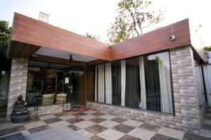 A modern building with a stone facade, large windows, and a checkered floor. - The Mannat Farms (Taoru)