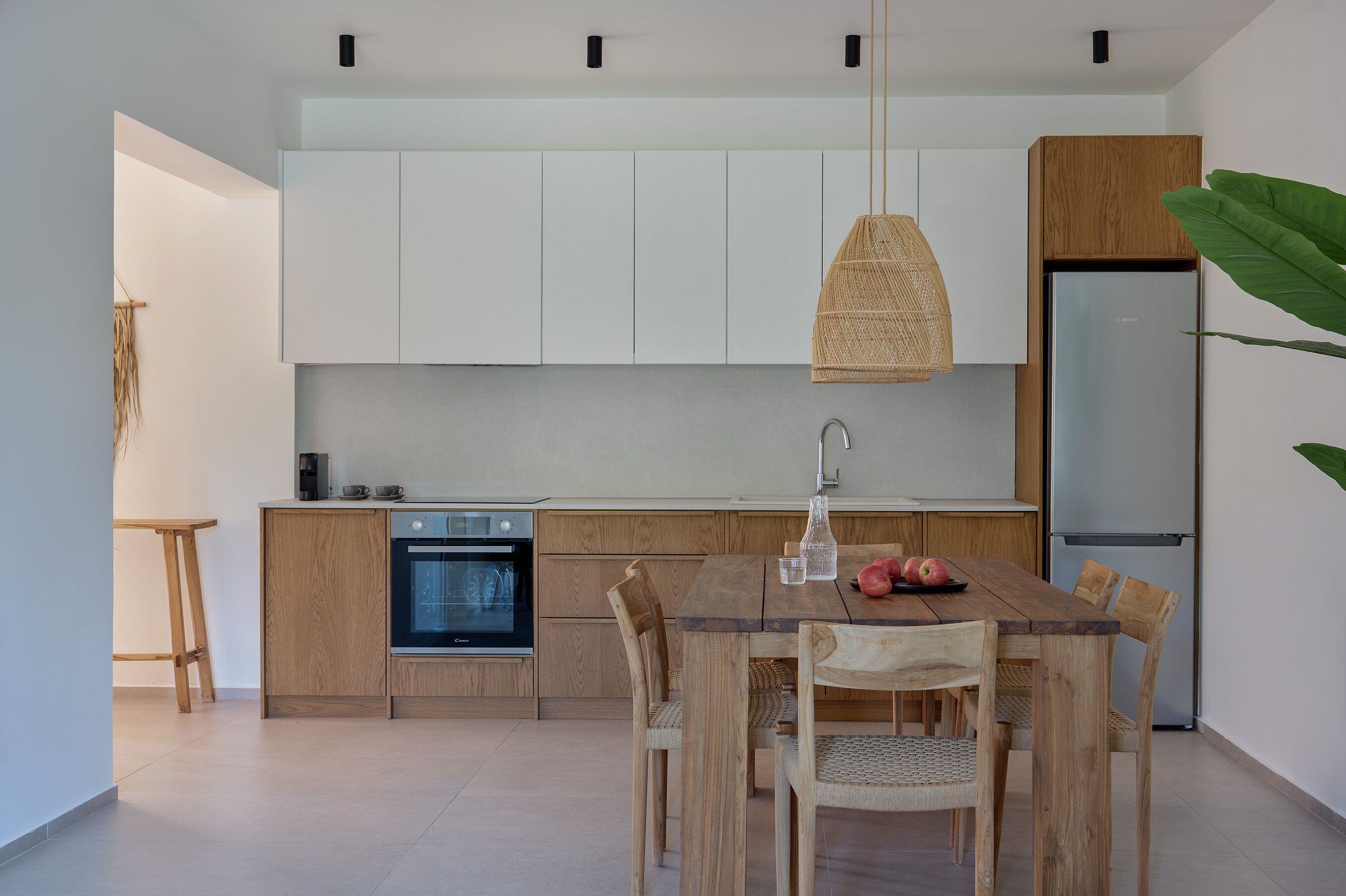 Une cuisine moderne avec des meubles en bois, un four encastré, un réfrigérateur en acier inoxydable et une table à manger avec des chaises.