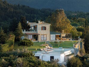 Una casa moderna con fachada de piedra, ventanas amplias y una terraza con techo de cristal.