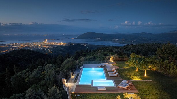 Ein Pool mit Liegestühlen und Blick auf die Stadt im Abendlicht.