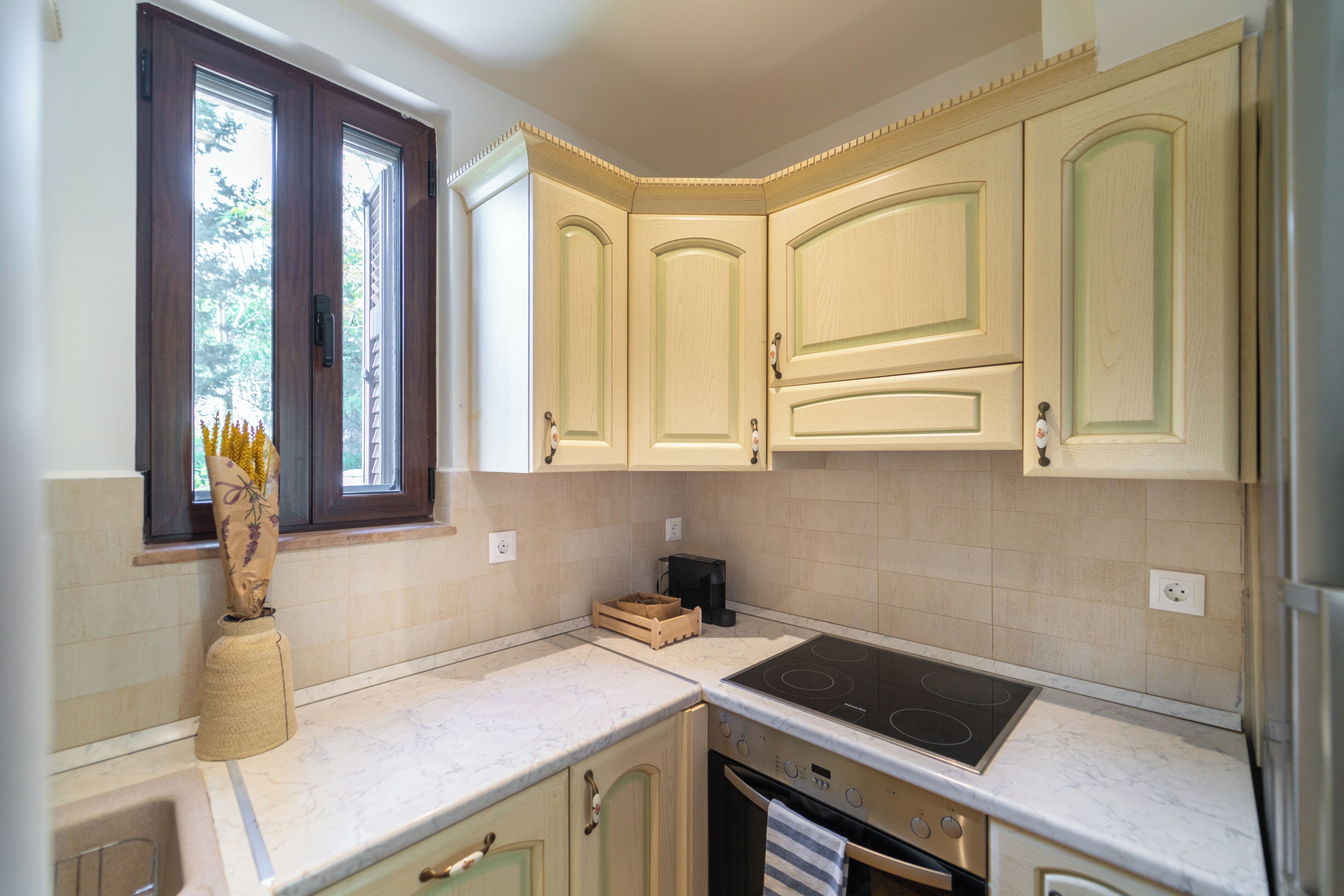 A kitchen with a window, a stove, cabinets, and a countertop.