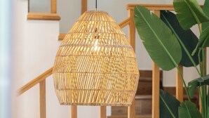 Ein Essbereich mit einem runden Holztisch, Korbstühlen und einer hängenden Lampenschirm aus Rattan.