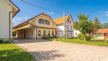 A residential area with a paved driveway leading to a house with a sloped roof and a balcony.
