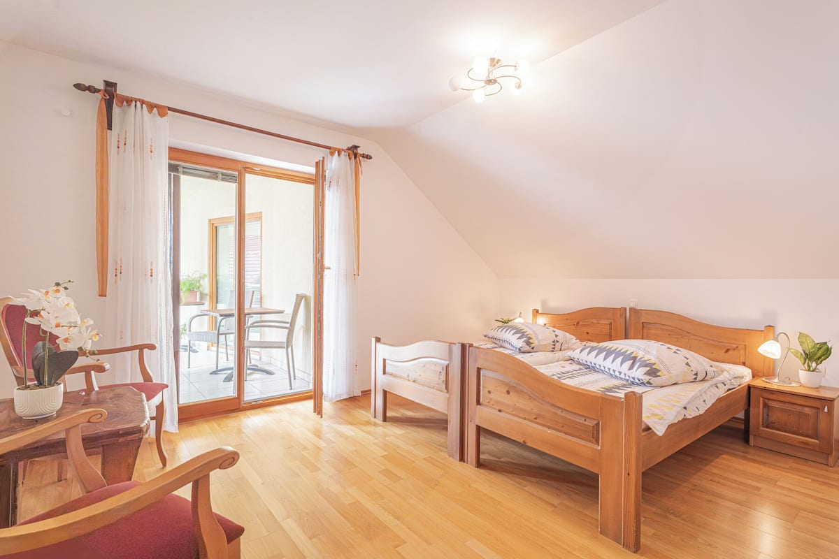 Un dormitorio con una cama de madera, una mesita de noche, una silla y una mesa con una planta en maceta.