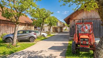 A rural street with a parked car and a red tractor.