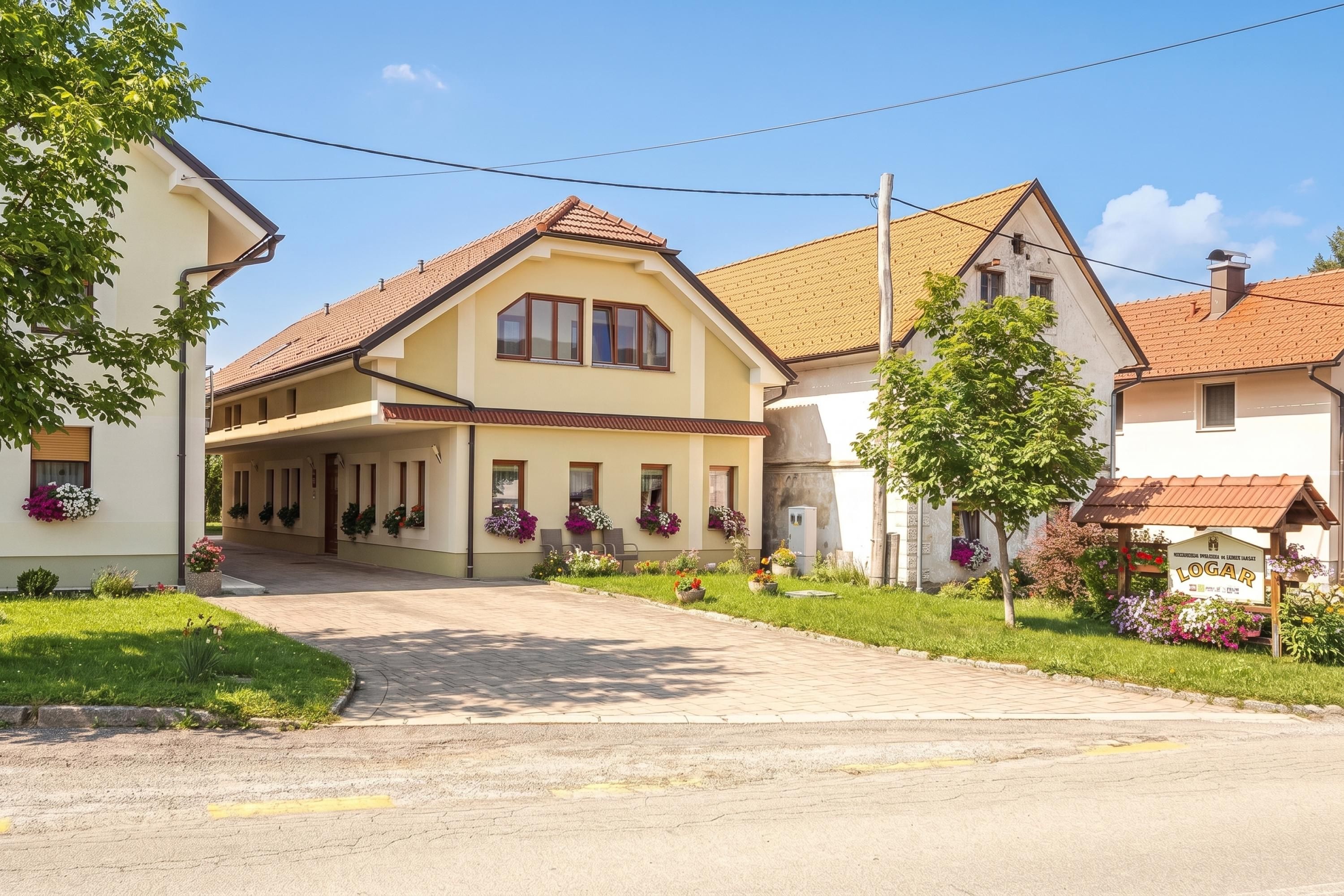 A two-story building with a sloped roof, a covered entrance, and a garden with flowers.