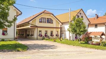 A two-story building with a sloped roof, a covered entrance, and a garden with flowers.