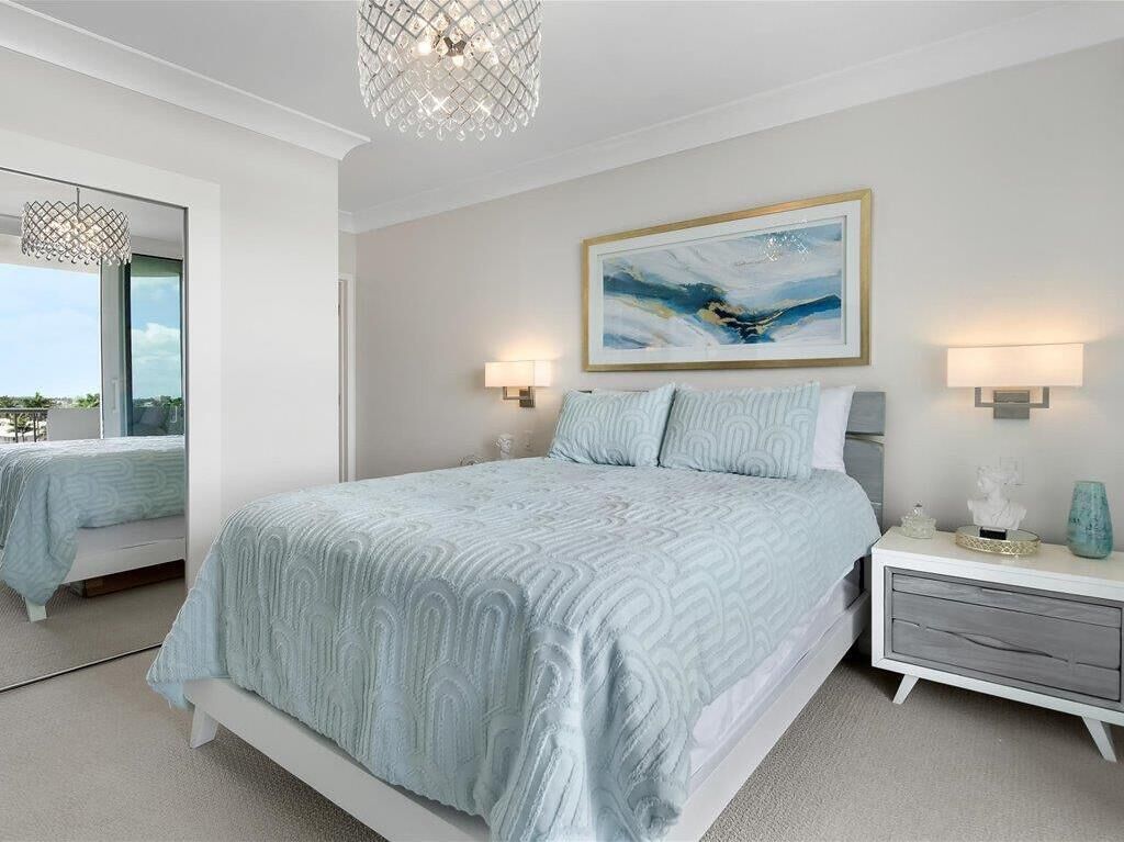 A bedroom with a large bed, bedside lamps, a wall-mounted painting, and a nightstand.